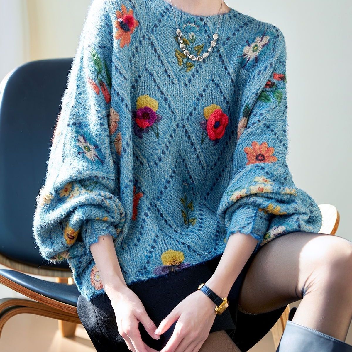 Elegancki i wygodny, dzianinowy sweter w kolorze niebieskim, z okrągłym dekoltem, ażurowym wzorem i kwiatowymi zdobieniami.