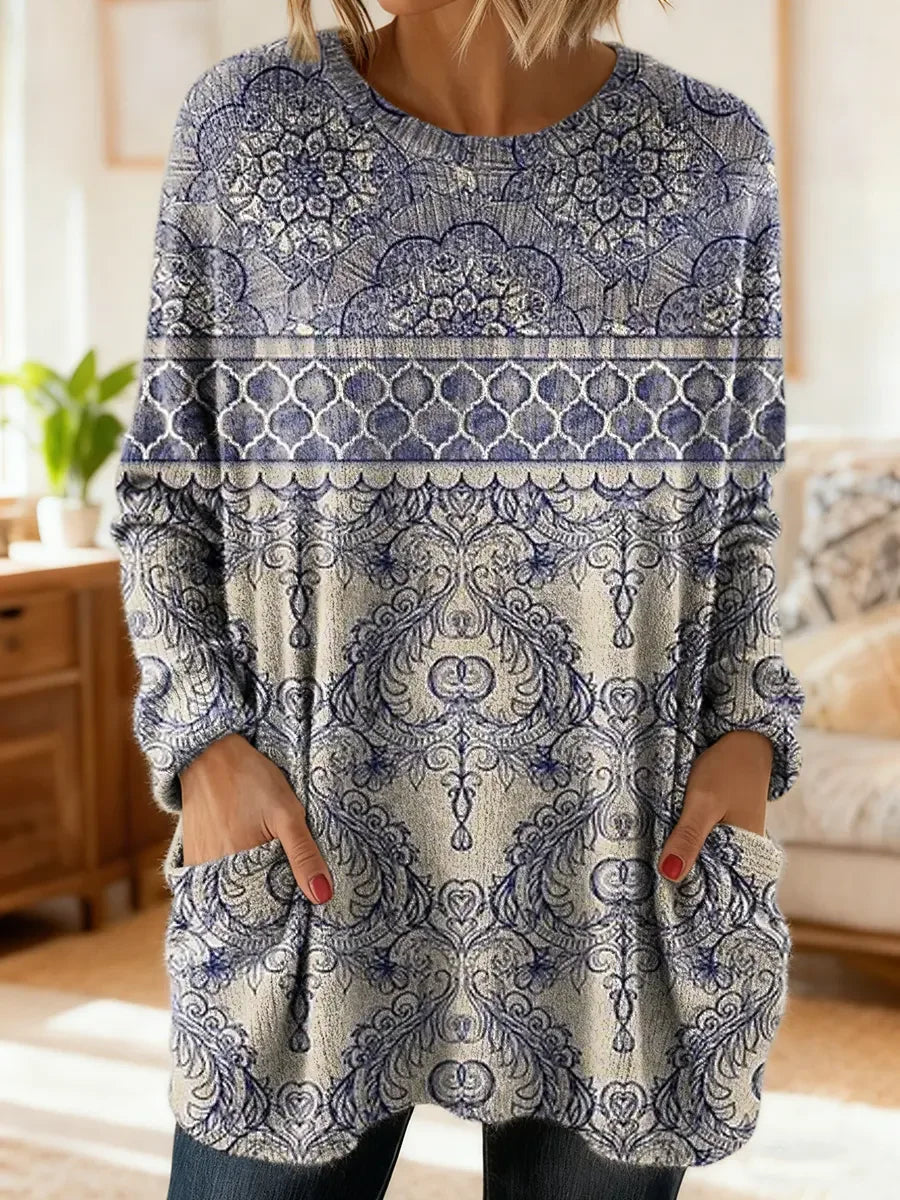 Elegancki i wygodny sweterek kaszmirowy ze wzorem w fioletowe kwiaty, z okrągłym dekoltem i kieszeniami.