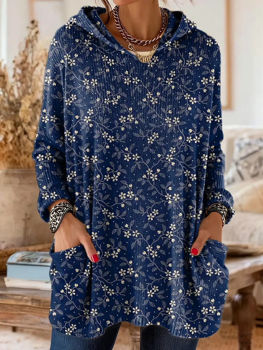 Elegancki i wygodny granatowy sweter kaszmirowy ozdobiony jest delikatnym białym wzorem kwiatowym. Posiada kaptur i kieszenie.