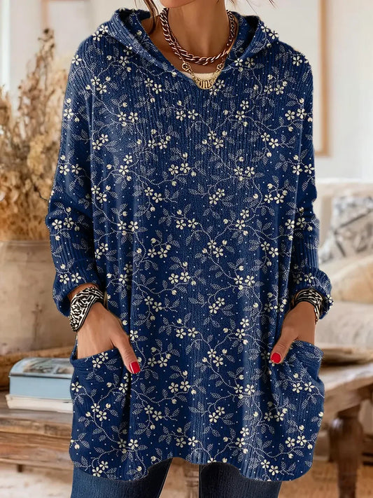 Elegancki i wygodny granatowy sweter kaszmirowy ozdobiony jest delikatnym białym wzorem kwiatowym. Posiada kaptur i kieszenie.