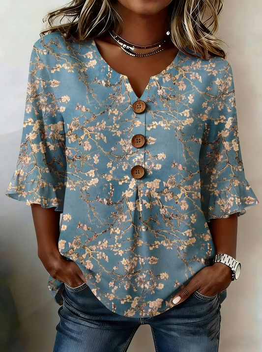Elegancka i wygodna niebieska koszula damska z pięknym kwiatowym nadrukiem, dekoltem w serek i plisowanymi mankietami.