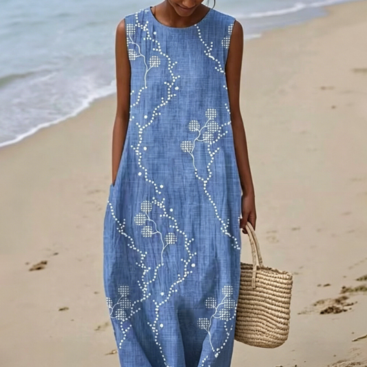 Ta elegancka i wygodna niebieska sukienka bez rękawów wyróżnia się minimalistycznym, białym nadrukiem kwiatowym, który podkreśla wyrafinowany i elegancki styl.