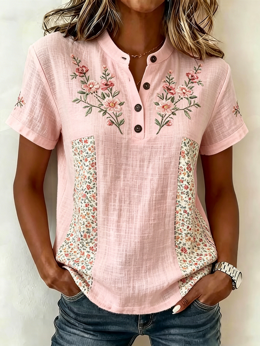 Wygodna, różowa, damska koszula z krótkim rękawem na lato, ozdobiona kwiatowym nadrukiem i zapinana na guziki przy dekolcie.