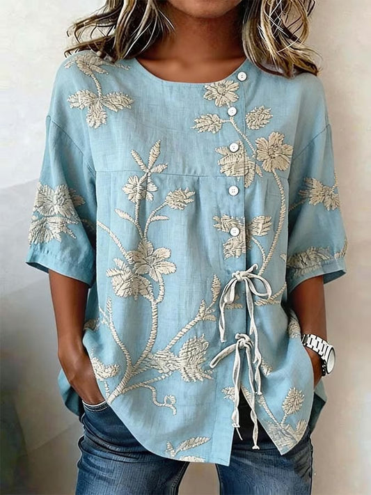 Ta jednokolorowa damska koszula ma nadruk w kolorze złotym, kwiatowy wzór oraz zapięcie na guziki i krawat. Jest luźna, wygodna, uniwersalna i praktyczna.