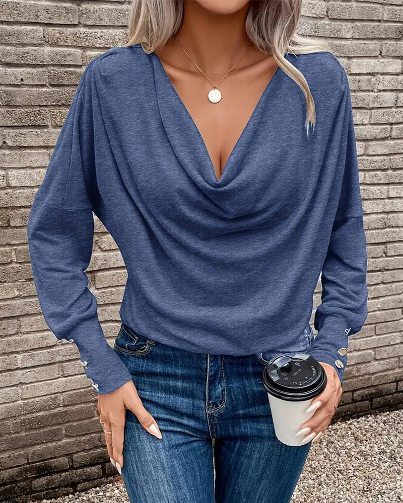 Ten stylowy i uniwersalny top w jednolitym kolorze ma plisowany design, który jest zarówno wyszczuplający, jak i elegancki.