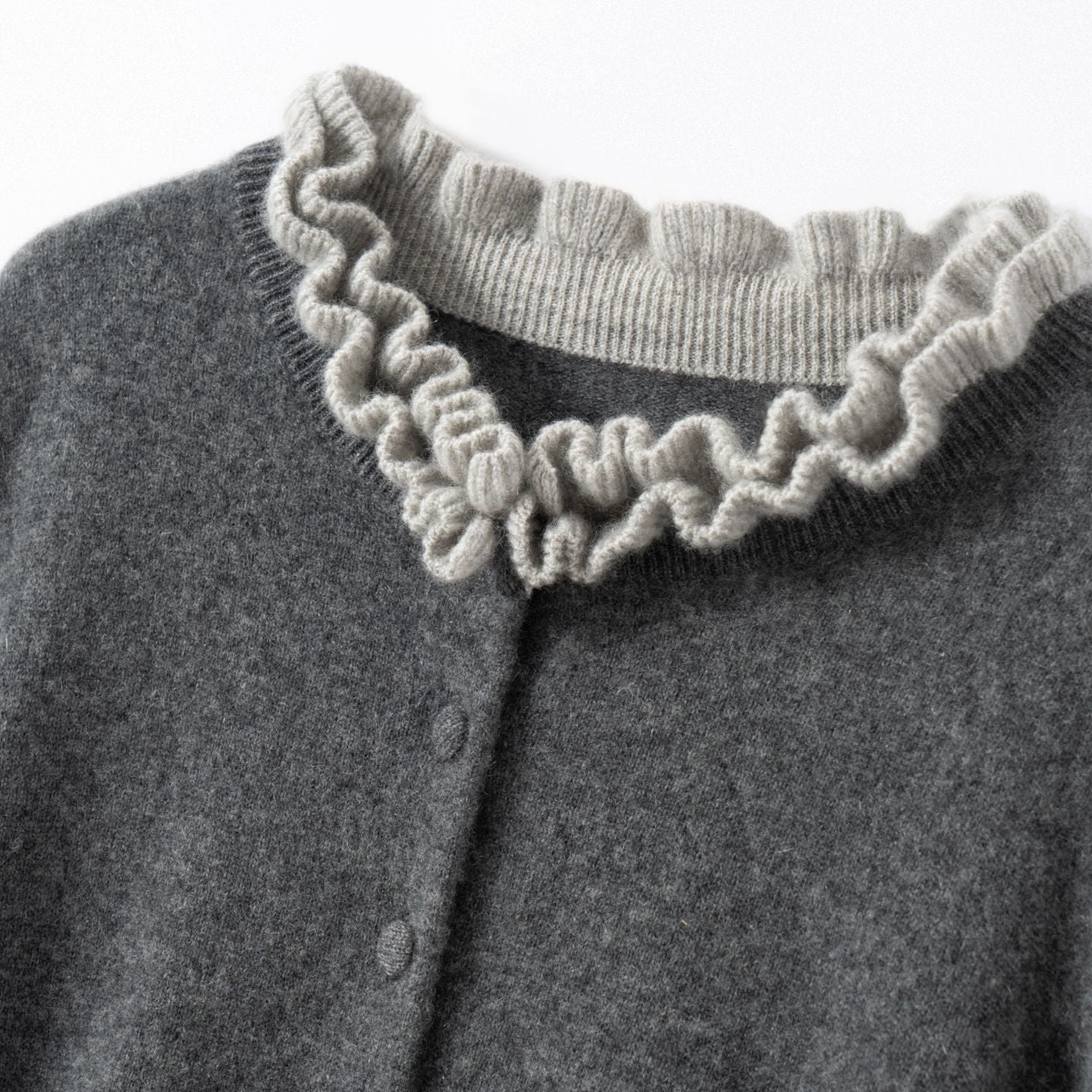 Elegancki i wygodny dwuczęściowy kardigan w jednolitym kolorze z kontrastującymi dzianinowymi falbankami przy kołnierzu i mankietach.