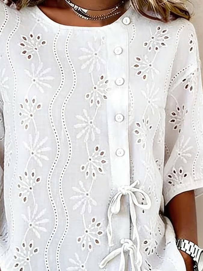 Ta jednokolorowa damska koszula wyróżnia się wyciętym wzorem kwiatowym, guzikami i krawatem, przez co jest uniwersalnym elementem garderoby.