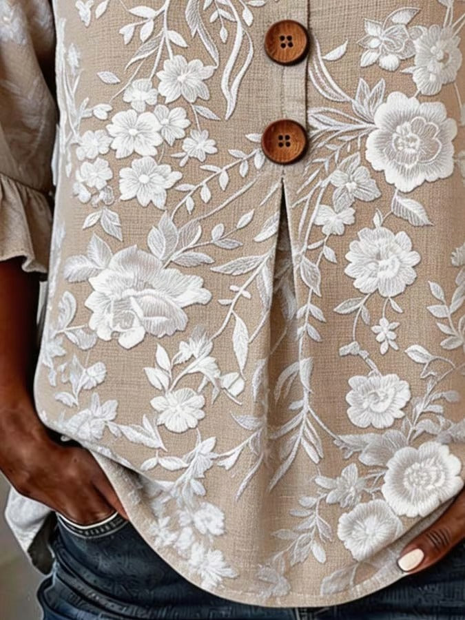 Elegancka i uniwersalna damska letnia koszula w kolorze khaki z dekoltem w serek, kwiatowym nadrukiem i falbankami przy mankietach.
