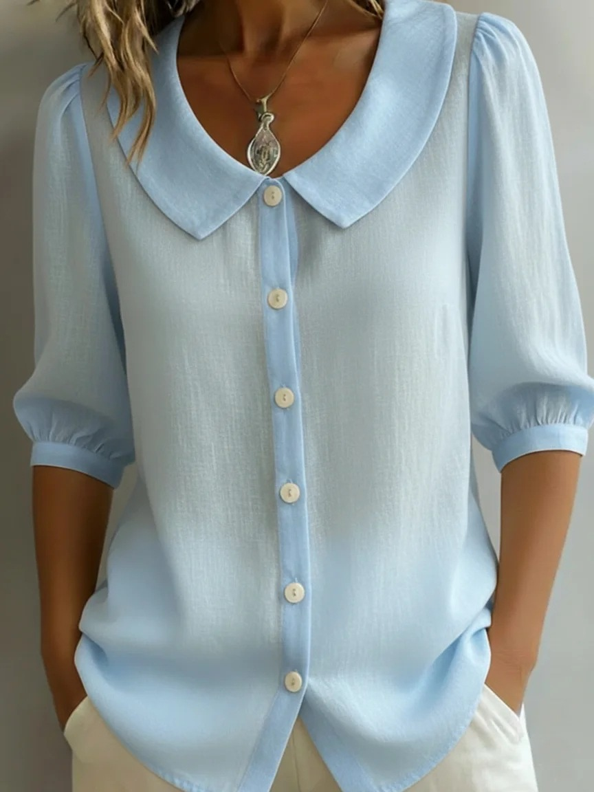 Elegancka i wygodna monochromatyczna koszula z krótkim rękawem i kołnierzykiem typu Piotruś Pan oraz dopasowanymi mankietami.