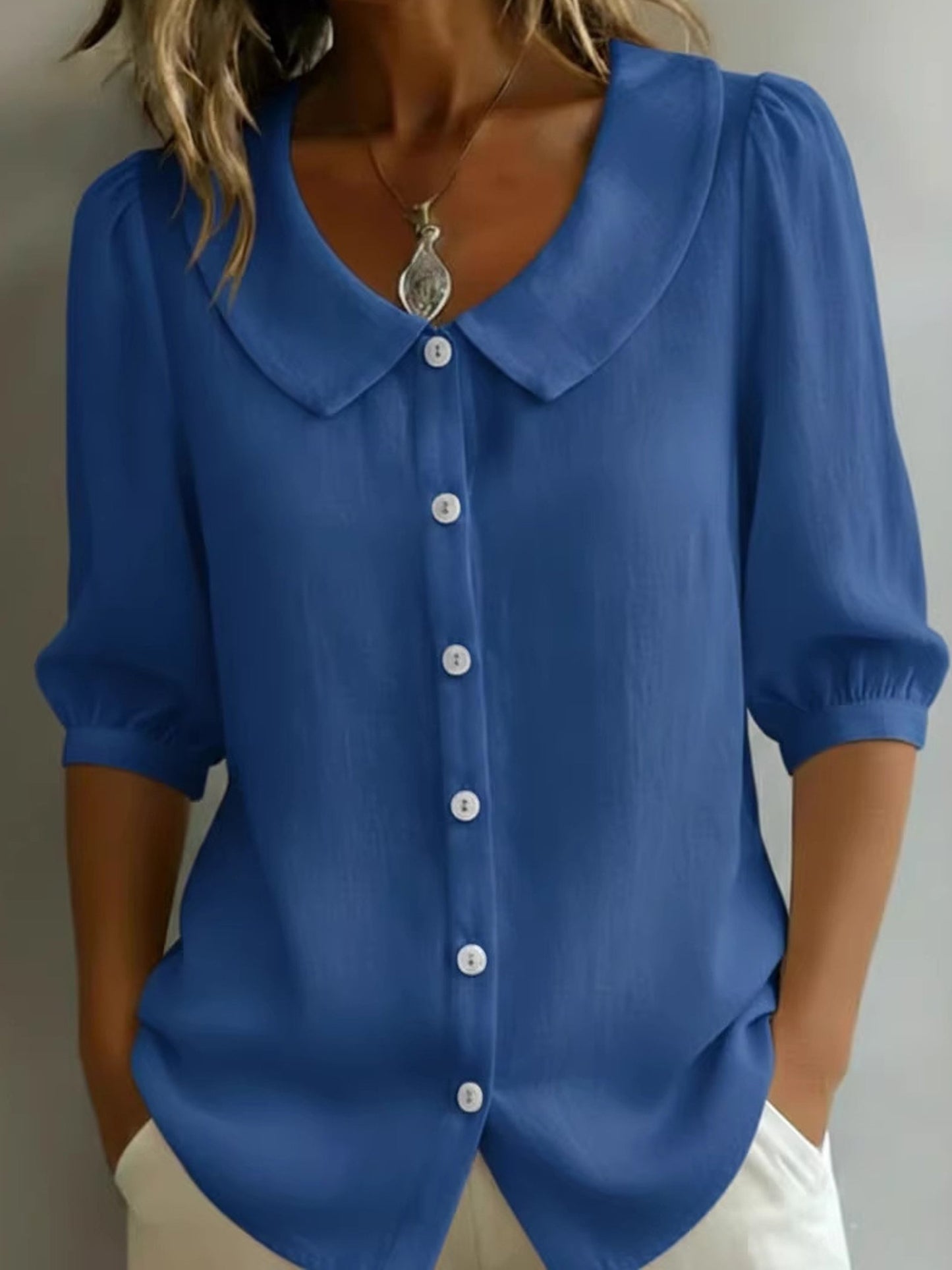 Elegancka i wygodna monochromatyczna koszula z krótkim rękawem i kołnierzykiem typu Piotruś Pan oraz dopasowanymi mankietami.