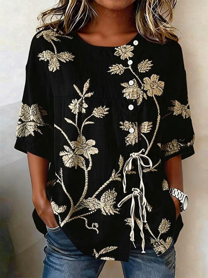 Ta jednokolorowa damska koszula ma nadruk w kolorze złotym, kwiatowy wzór oraz zapięcie na guziki i krawat. Jest luźna, wygodna, uniwersalna i praktyczna.