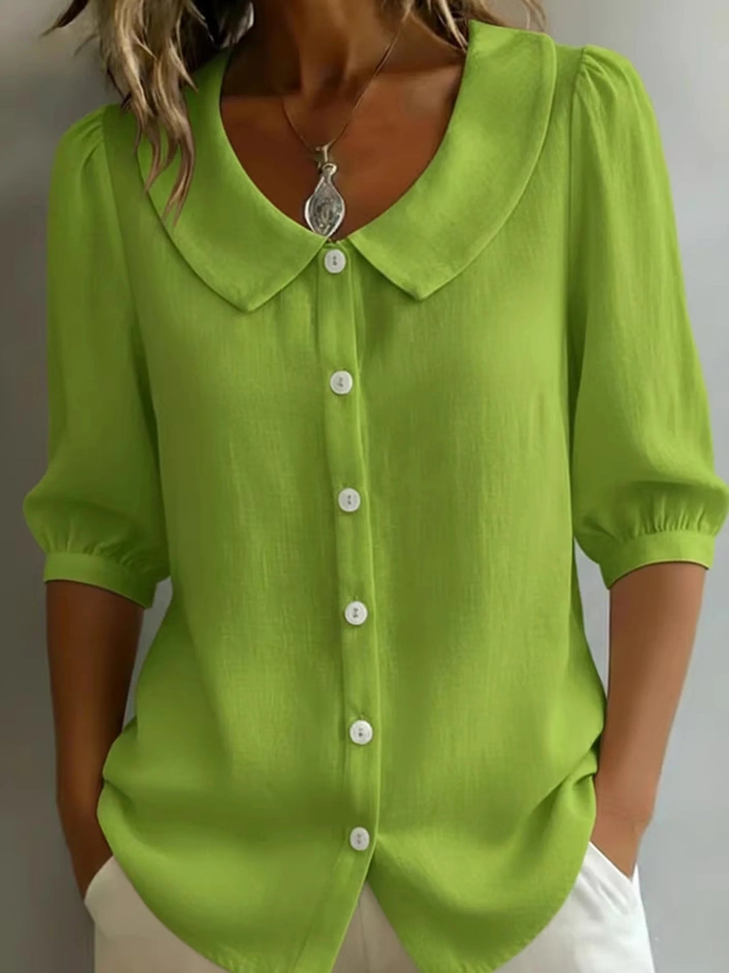 Elegancka i wygodna monochromatyczna koszula z krótkim rękawem i kołnierzykiem typu Piotruś Pan oraz dopasowanymi mankietami.