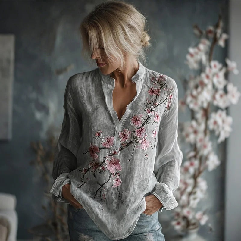Lekka i przewiewna, jednokolorowa damska koszula ozdobiona nadrukiem przedstawiającym różowy kwiat śliwki, emanująca eleganckim urokiem.