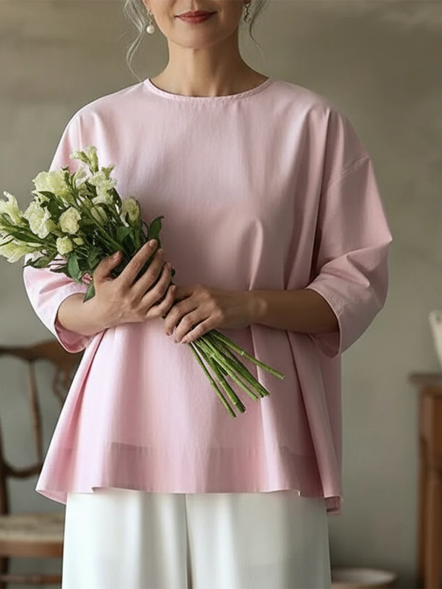 Elegancka i wygodna koszula w jednolitym kolorze z długim rękawem, zapinana z tyłu na guziki, o świeżym i czystym wzornictwie.